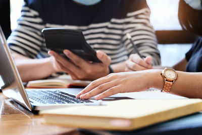 Midsection of man using mobile phone on table