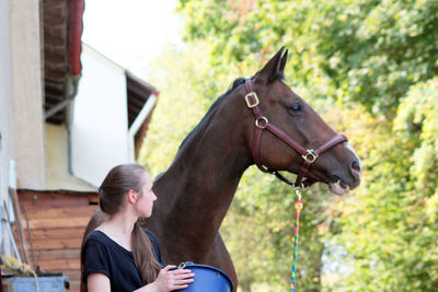 Full length of a young woman with horse in background