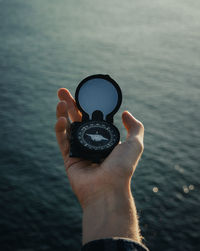 Midsection of person holding umbrella against sea