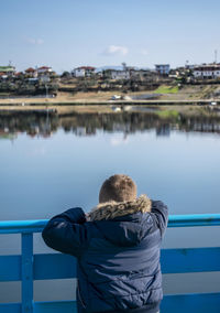 Rear view of man on lake against sky