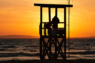 Silhouette man looking at sea against sky during sunset