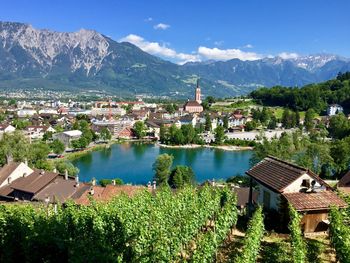 Panoramic view of townscape by lake and mountains against sky