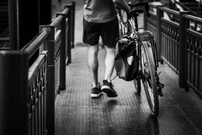 Low section of man with bicycle walking on footbridge