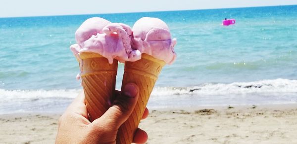 Midsection of woman holding ice cream on beach