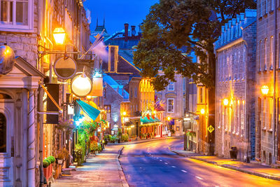 Illuminated street amidst buildings at night