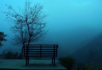 Bare tree on landscape against sky