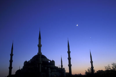 Low angle view of buildings against clear blue sky at night