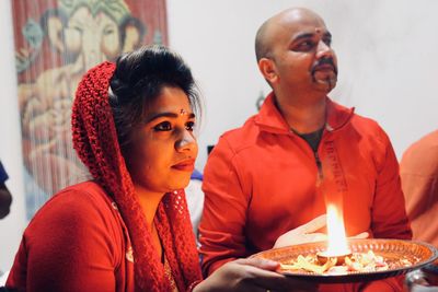 Couple looking away while holding religious offering during ceremony at home