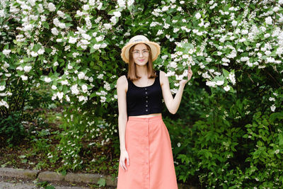 Portrait of beautiful young woman standing against plants