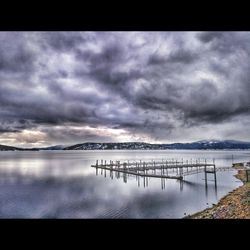 Pier on sea against cloudy sky