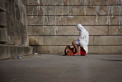 Man face wrapped in textile while sitting by wall