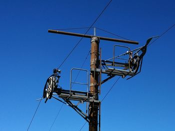 Low angle view of crane against clear blue sky