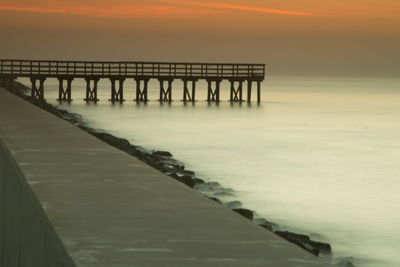 Pier over sea against sky during sunset