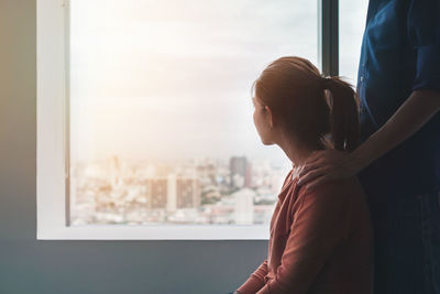 Woman looking through window at home