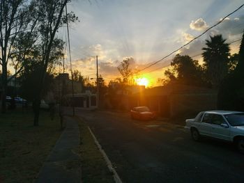 Cars on road against sky at sunset