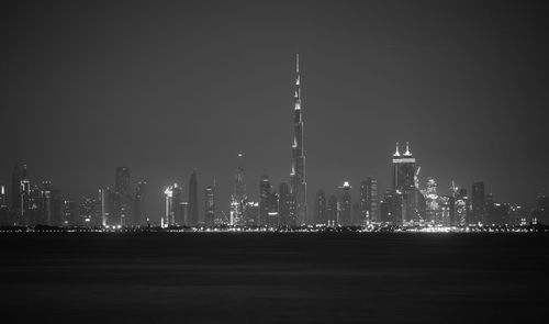 Burj khalifa lake in front of illuminated urban skyline against clear sky