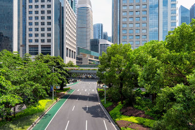 Road amidst trees and buildings in city