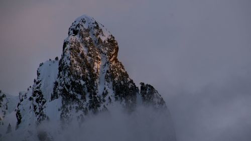 Low angle view of rock formation against sky during winter