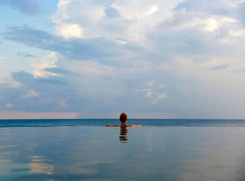 Rear view of man in sea against sky