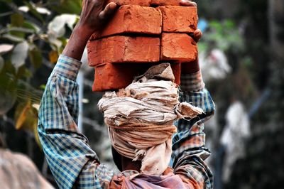 Rear view of worker carrying bricks at construction site