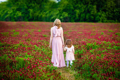 Rear view of woman standing with daughter on flowering land
