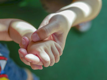 Cropped image of child and parent holdings hands outdoors