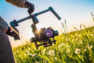 Man holding drone on field against sky