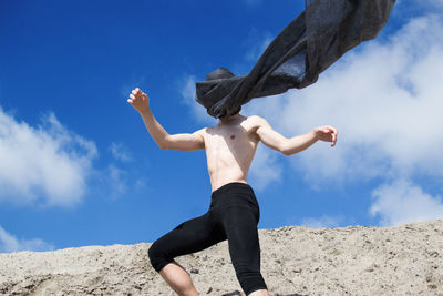 Low angle view of shirtless man standing against sky