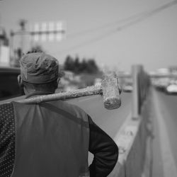 Rear view of worker holding sledgehammer while standing outdoors