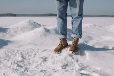 Young boy in winter boots standing near frozen lake. sunny winter day.