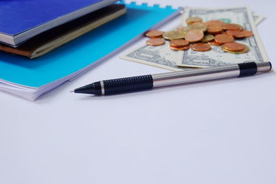 Close-up of book and calculator by pen on white background