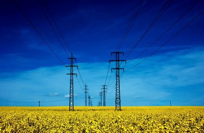 Electricity pylon on field against blue sky