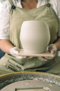 Midsection of woman with clay pot at workshop