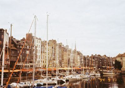 Sailboats moored in harbor against buildings in city