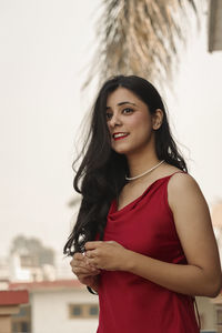 Portrait of young woman standing against wall