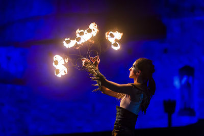 Side view of woman standing against illuminated light