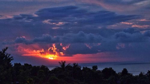 Scenic view of sea against cloudy sky at sunset