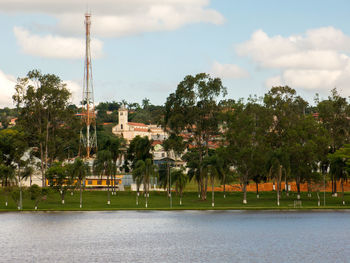 Trees by lake against sky in city