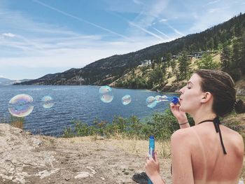 Rear view of woman blowing bubbles while sitting on land