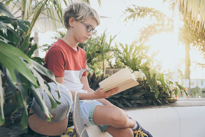 Boy reading book while sitting in park