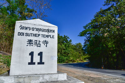 Information sign by road against clear blue sky