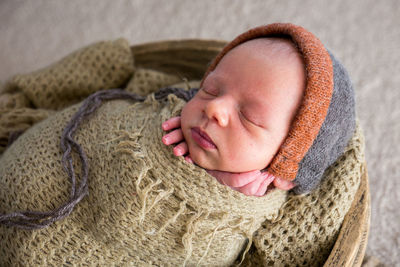Newborn in a basket in a green winding and a warm hat