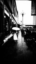 Rear view of woman walking on wet street in city