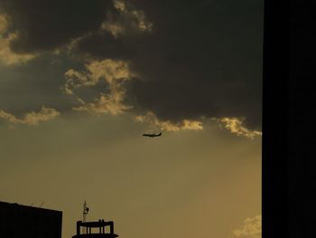 Low angle view of silhouette airplane against sky during sunset