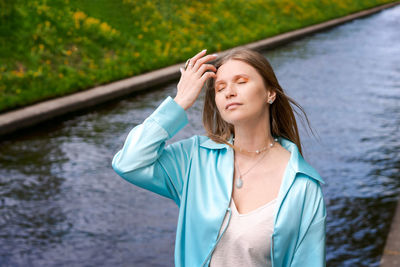 Young woman standing against lake