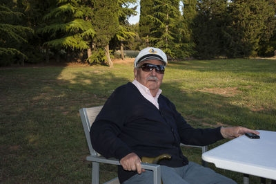 Man wearing sunglasses sitting on seat in park