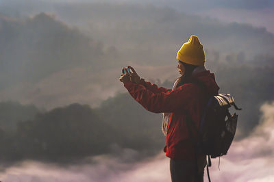 Side view of woman wearing knit hat photographing outdoors