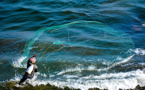 Rear view of fisherman fishing in sea