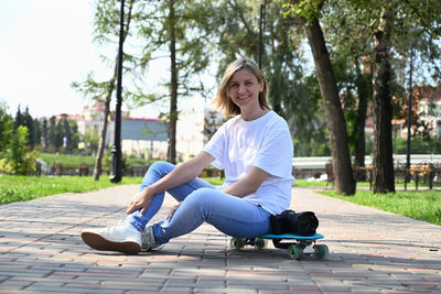 Portrait of woman sitting on footpath