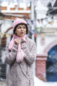 A stylish woman in pastel-colored warm clothes outdoors in the city in winter.snowfall,cold weather.